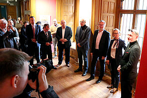 Die Eröffnung der Ausstellung. Menschen haben sich versammelt. 