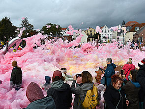 Viele Menschen stehen um ein großes Feld aus rosa Schaum.