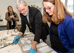 Detlef Jantzen und Bettina Martin stehen nebeneinander an einem Tisch, auf dem die gefundenen Schätze liegen. 