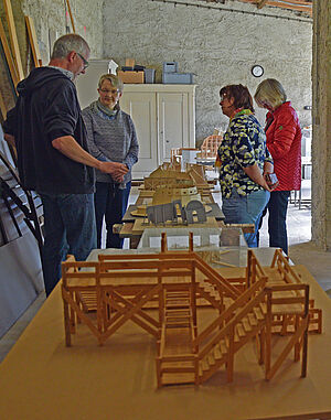 Vier Personen stehen im Atelier von Rolf Wicker und unterhalten sich.