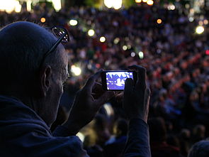 Ein Zuschauer macht mit seinem Handy ein Foto von der Bühne. 