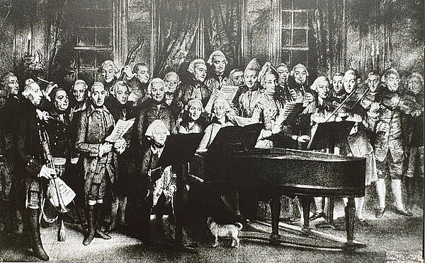 Eine Schwarz-Weiß-Aufnahme. Viele Musiker stehen dicht beieinander. Sie haben Instrumente in der Hand. Ein Mann sitzt am Klavier.