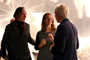 Drei Personen stehen vor einer Kunstinstallation.