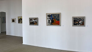 Zwei weiße Wände mit dunklen Bildern.