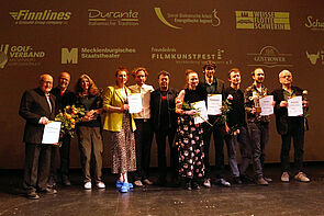 Gruppenbild der Sieger und Siegerinnen auf der Bühne.