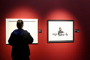 Eine junge Frau betrachtet die Bilder in der Ausstellung.