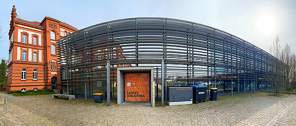 Ein langgestrickter Glasanbau mit breiter Fensterfront und der Eingangstür zur Landesbibliothek.