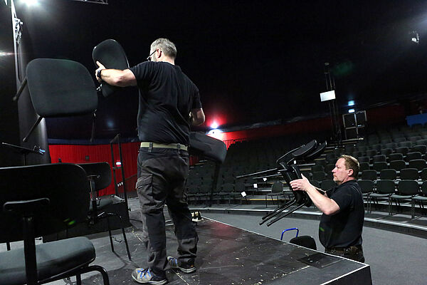 Zwei Männer schleppen Stühle.