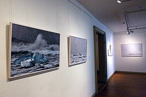 Blick in einen Ausstellungsraum. Vier Bilder hängen an der Wand. 