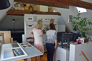 Vier Leute stehen im Atelier von Gerhard Stromberg und unterhalten sich.