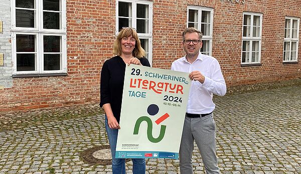 Eine Frau und ein Mann halten ein Plakat über die Literaturtage hoch.