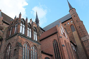 Nahaufnahme einer Kirchenseite mit Fenstern, Türmen und Zinnen.