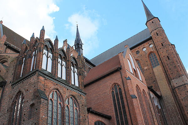 Nahaufnahme einer Kirchenseite mit Fenstern, Türmen und Zinnen.