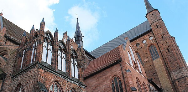 Nahaufnahme einer Kirchenseite mit Fenstern, Türmen und Zinnen.