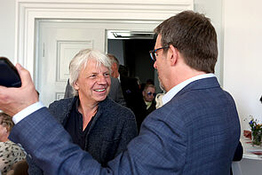 Zwei Männer begrüßen sich lachend.