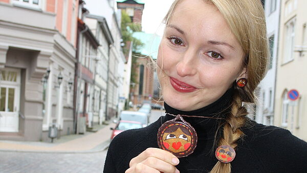 Nadja Bossert hält den bunten Anhänger ihrer Kette in der Hand. 