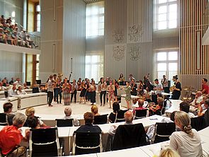 Der Plenarsaal ist voller Zuschauerinnen und Zuschauer sowie Musikerinnen und Musiker.