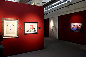 Bilder hängen an einer roten Wand.