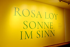 Das Thema dieser Ausstellung: Sonne im Sinn. Der Titel steht auf einer gelben Wand.