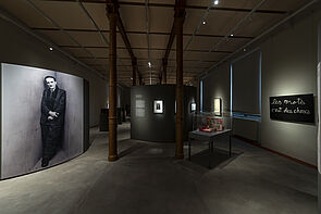 Ein nur leicht beleuchteter Ausstellungsraum. An den Wänden hängt moderne Kunst.