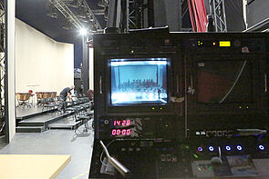 Blick durch einen Bildschirm auf die Bühne.