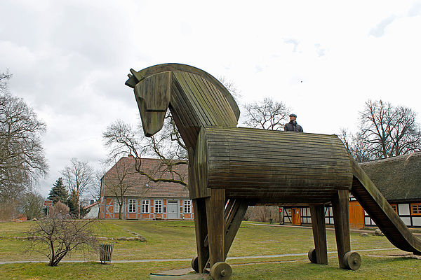 Ein Mann steht auf einem trojanischen Pferd. Das Pferd gehört zu einem Spielplatz.