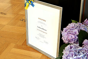 Eine gerahmte Urkunde steht auf dem Boden.