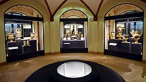 Im Ausstellungsraum sind drei Vitrinen in die Wand eingelassen. Sie sind beleuchtet und mit Geschirr und Porzellan gefüllt.