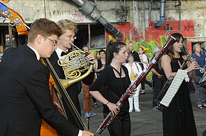 Vier Musikerinnen und Musiker stehen in einer der Hallen und spielen.