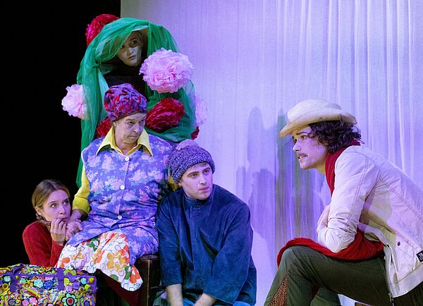 Vier Personen an der linken Bildseite schauen einen Mann an der rechten Bildseite an.