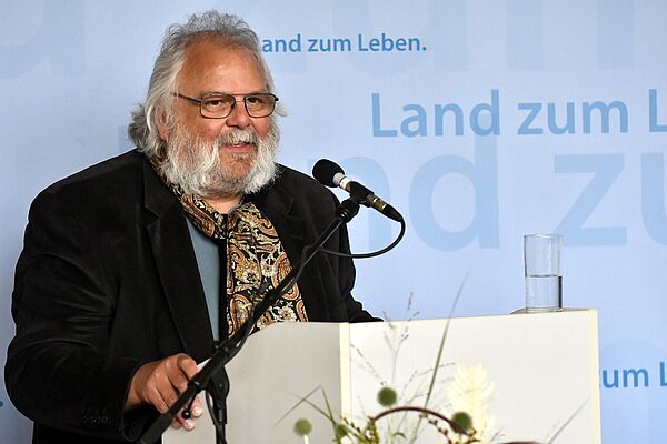 Wolfgang Bordel steht an einem Rednerpult und spricht.