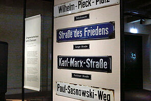 Alte Straßenschilder hängen übereinander in der Ausstellung. 
