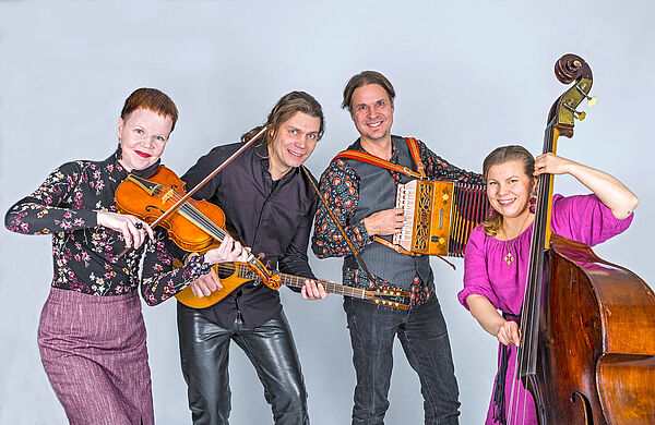 Zwei Männer und zwei Frauen. Sie stehen nebeneinander und spielen Instrumente.