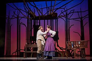 Ein Mann und eine Frau stehen auf der Bühne und sprechen miteinander.