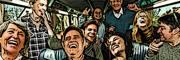 Neun Frauen und Männer sitzen und stehen in einem Bus und lachen herzhaft.