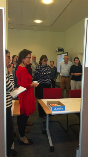 Neun Frauen und Männer stehen in einem Raum blicken auf eine Flipchart.