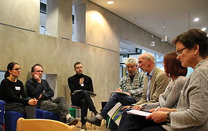 Drei Frauen und vier Männer sitzen sich in einem der Workshops gegenüber und unterhalten sich. 