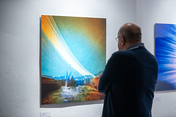 Ein Mann betrachtet ein Bild an einer Wand.