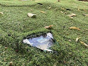 Auf der Wiese liegt ein bedrucktes Papier.