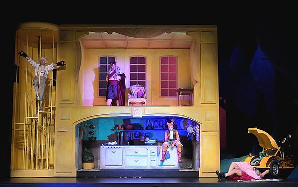 Ein Haus wie ein Puppenhaus auf einer Theaterbühne