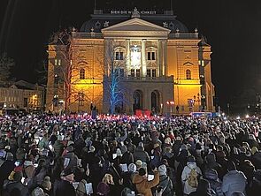 Ein Platz voller Menschen. Sie singen Weihnachtslieder.