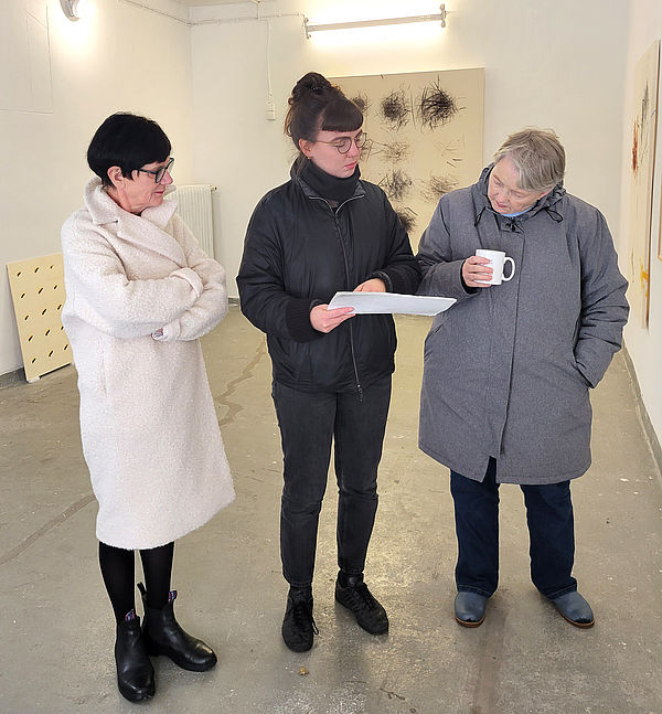 Dr. Kornelia Röder (l.) und Dr. Merete Cobarg (r.) von der Kunstkommission sprechen mit Johanna Herrmann. Im Hintergrund ihre Kunstwerke. 