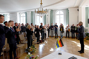 Viele Personen klatschen Beifall für einen Mann.