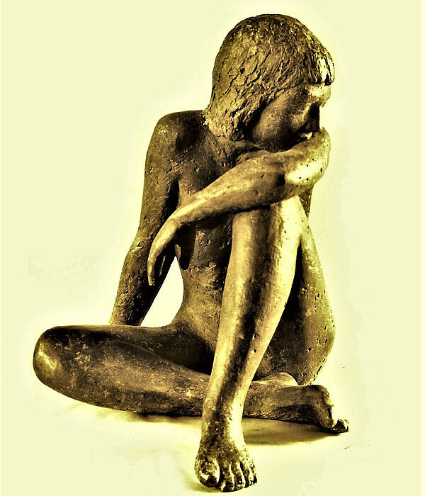 Eine Figur aus Bronze. Zu sehen ist eine junge Person, die sitzt. Ein Bein ist angewinkelt.