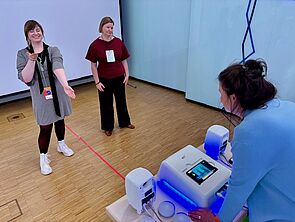 Zwei Frauen testen ein Gerät, das Bewegungen in Töne verwandelt.