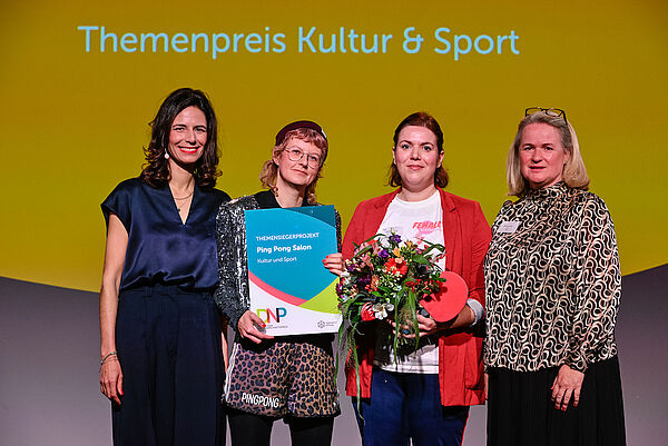 Preisverleihung auf der Bühne. Zwei Frauen werden ausgezeichnet.