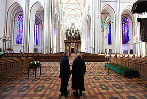 Zwei Männer stehen im Schweriner Dom, sie schauen sich die Kirchenfenster an.