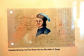 Hinter Glas hängt eine Zeichnung, die Reuter angefertigt hat. Es zeigt das Porträt eines Jungen. Daneben befinden sich handschriftliche Notizen.