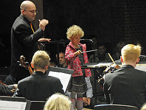 Ein kleines Mädchen dirigiert das Orchester.
