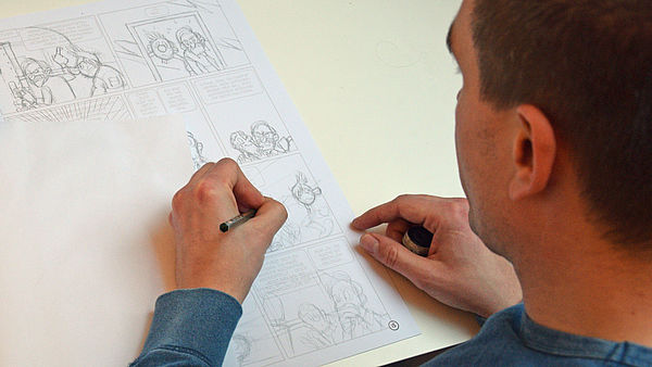 Stefan Pede zeichnet mit links an einem Comic.